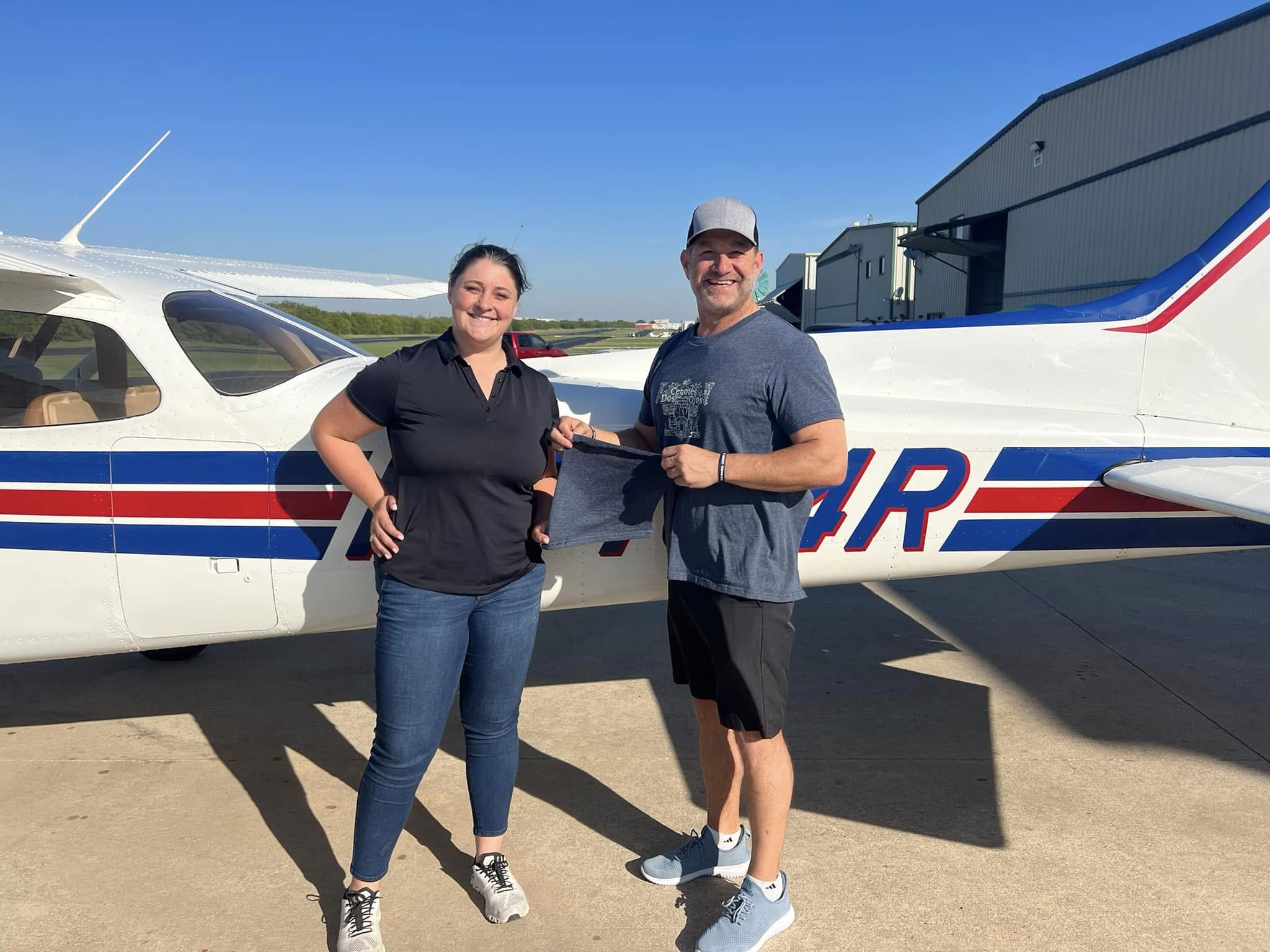 Student pilot participating in traditional shirt-tail cutting ceremony after first solo flight at Hicks Airfield